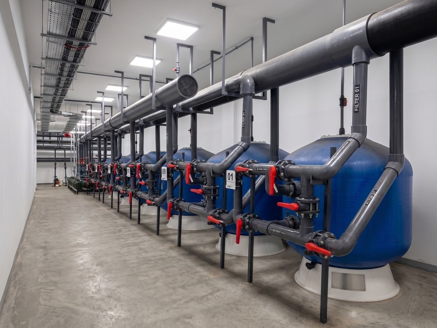 Commercial plant room with a row of sand filters and PVC manifolds